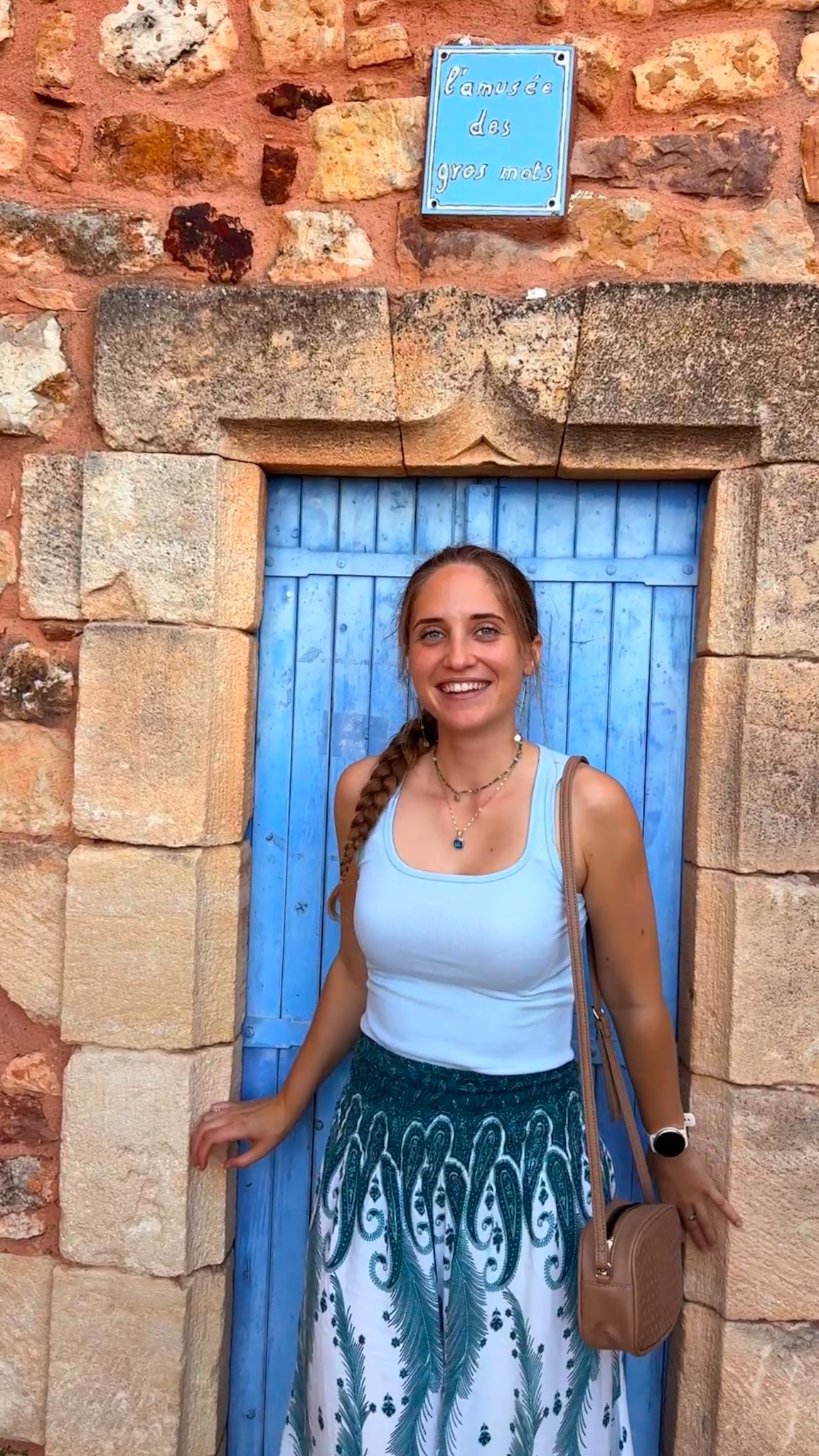 Gina smiling in front of a blue doorway